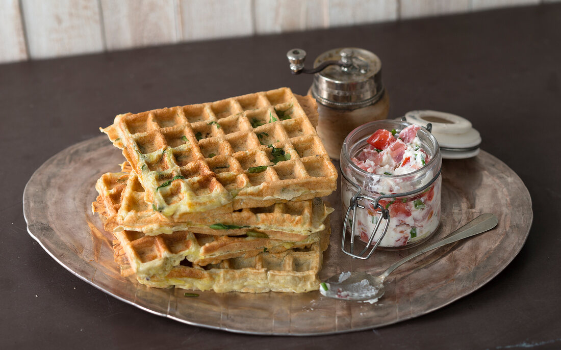 Stack of potato waffles with ham cream in glass jar on silver platter