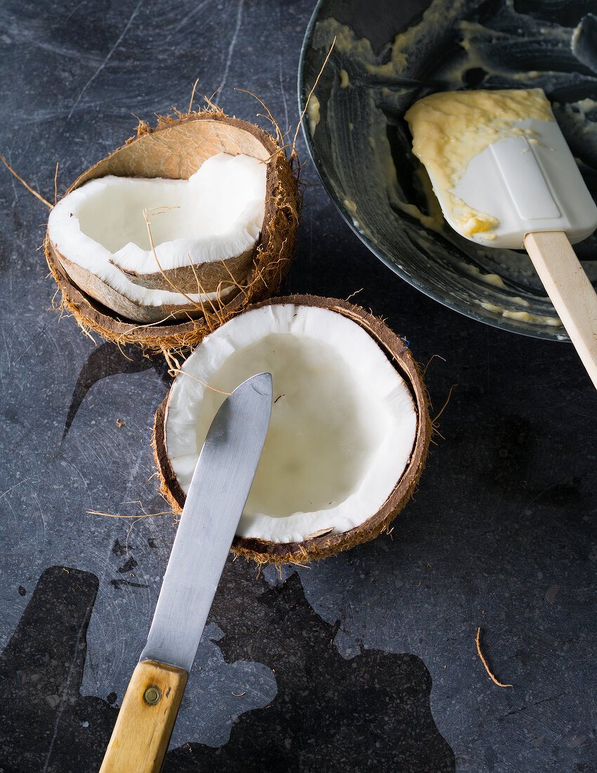 Halved coconut divided with knife for preparation of coconut cake, step 1