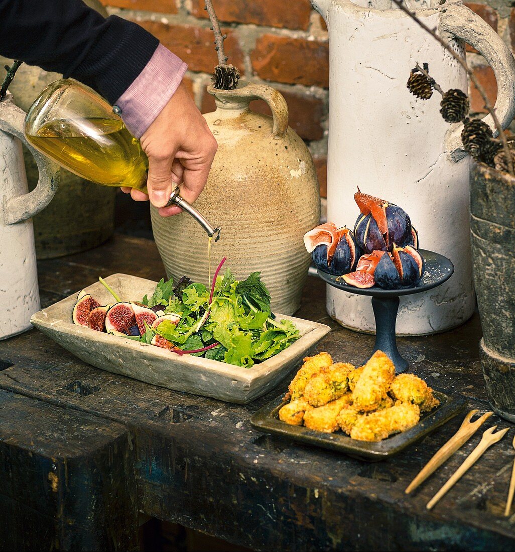 Oil being poured onto a salad on an appetiser buffet