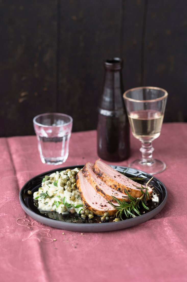 Roasted pork with risotto and rosemary on chopping board