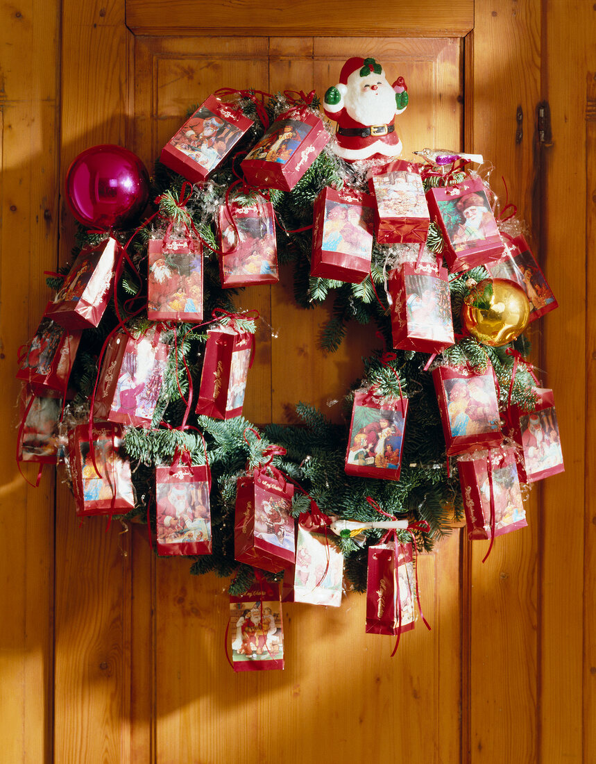 Christmas wreath decorated with gift bags hanging on door