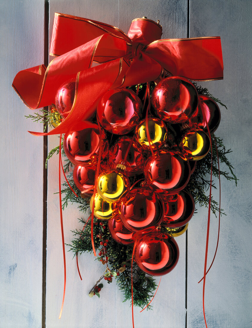 Bunch of Christmas baubles tied with ribbon hanging on wooden door