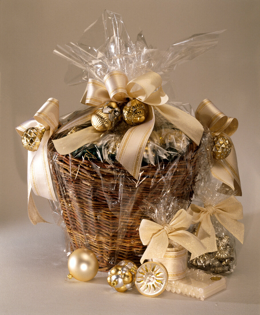 Basket with Christmas decorations of creme and gold colour wrapped in foil