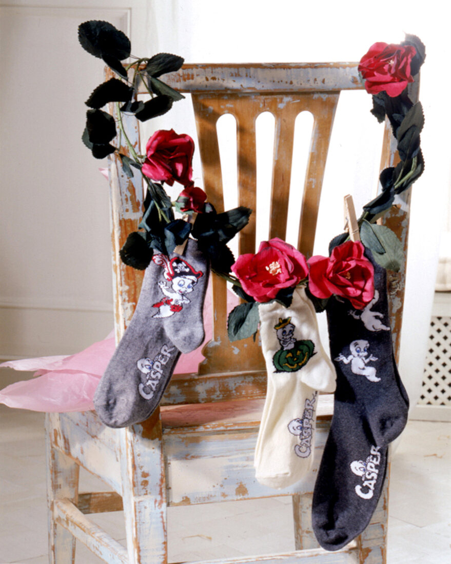"Casper"-Socken hängen an einer künstlichen Rosengirlande, Stuhl