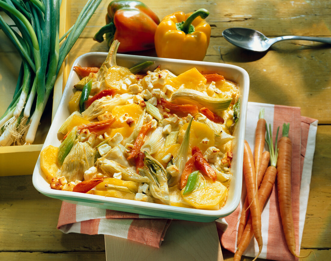 Vegetable gratin with feta cheese, fennel, carrots, potatoes and peppers on square plate