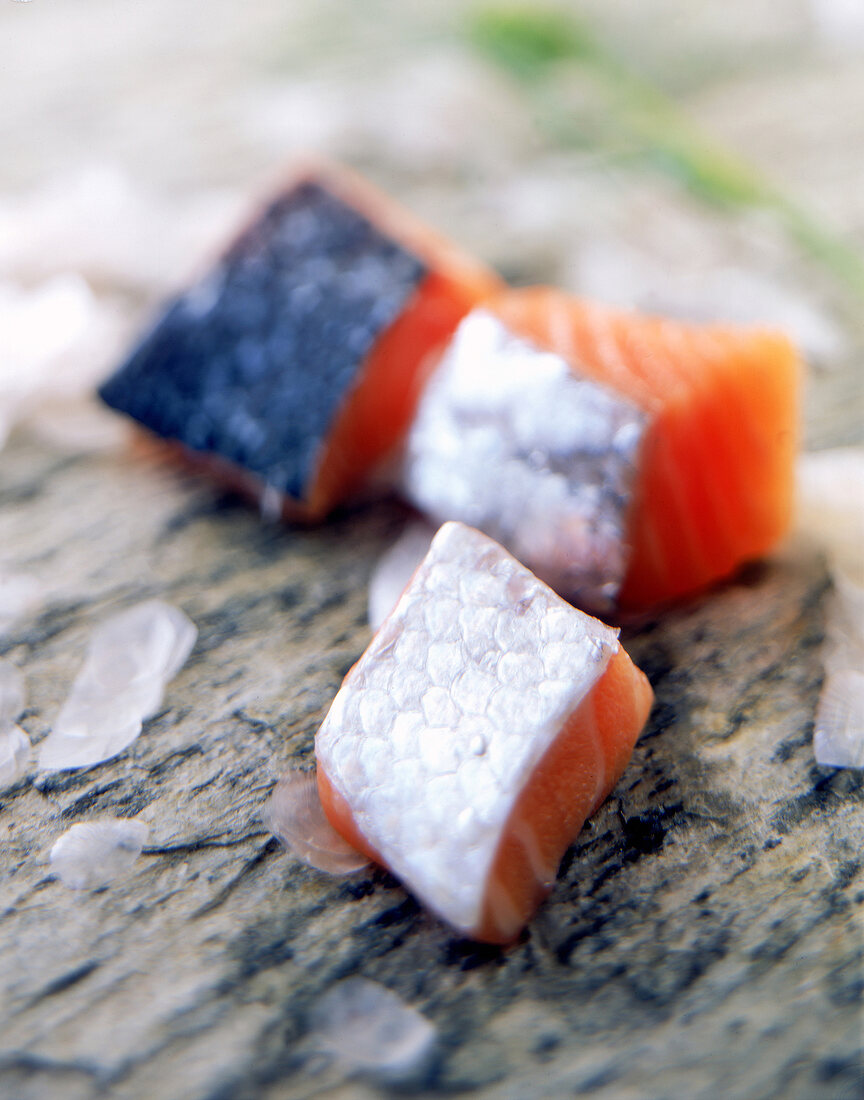 Roher Lachs in kleine Stücke geschnitten, davor Fischschuppen