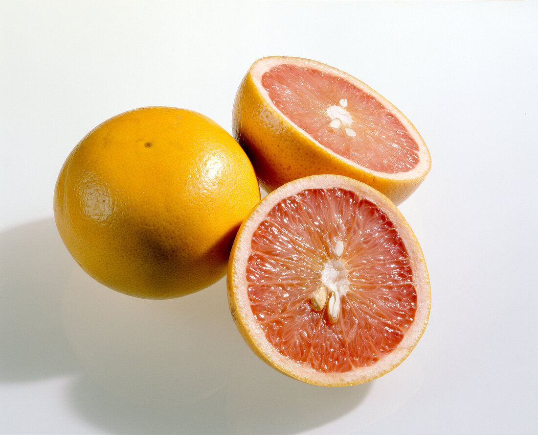 Close-up of whole and halved grapefruit with on white background