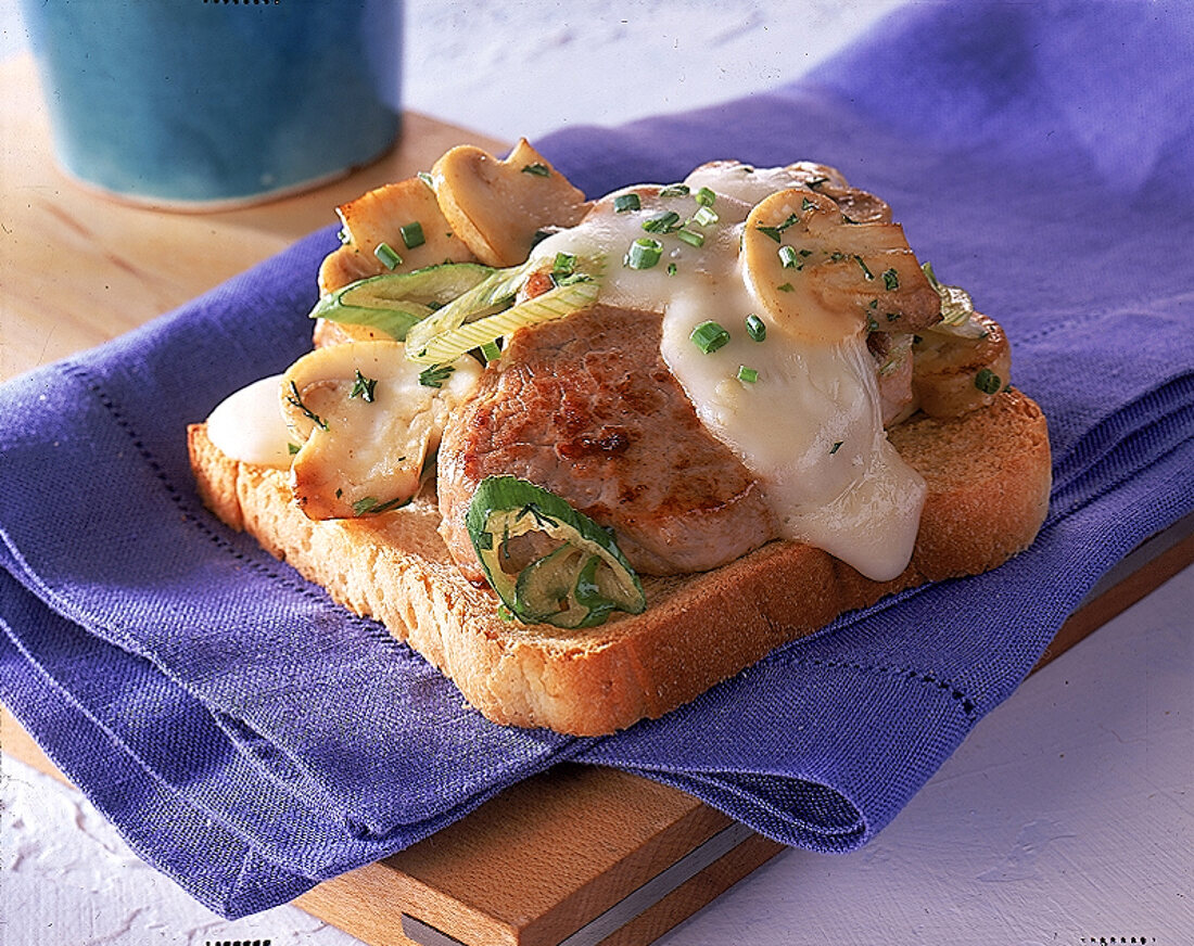 Schweinesteak auf Toast mit Lauch zwiebeln, Champignons und Kaese.