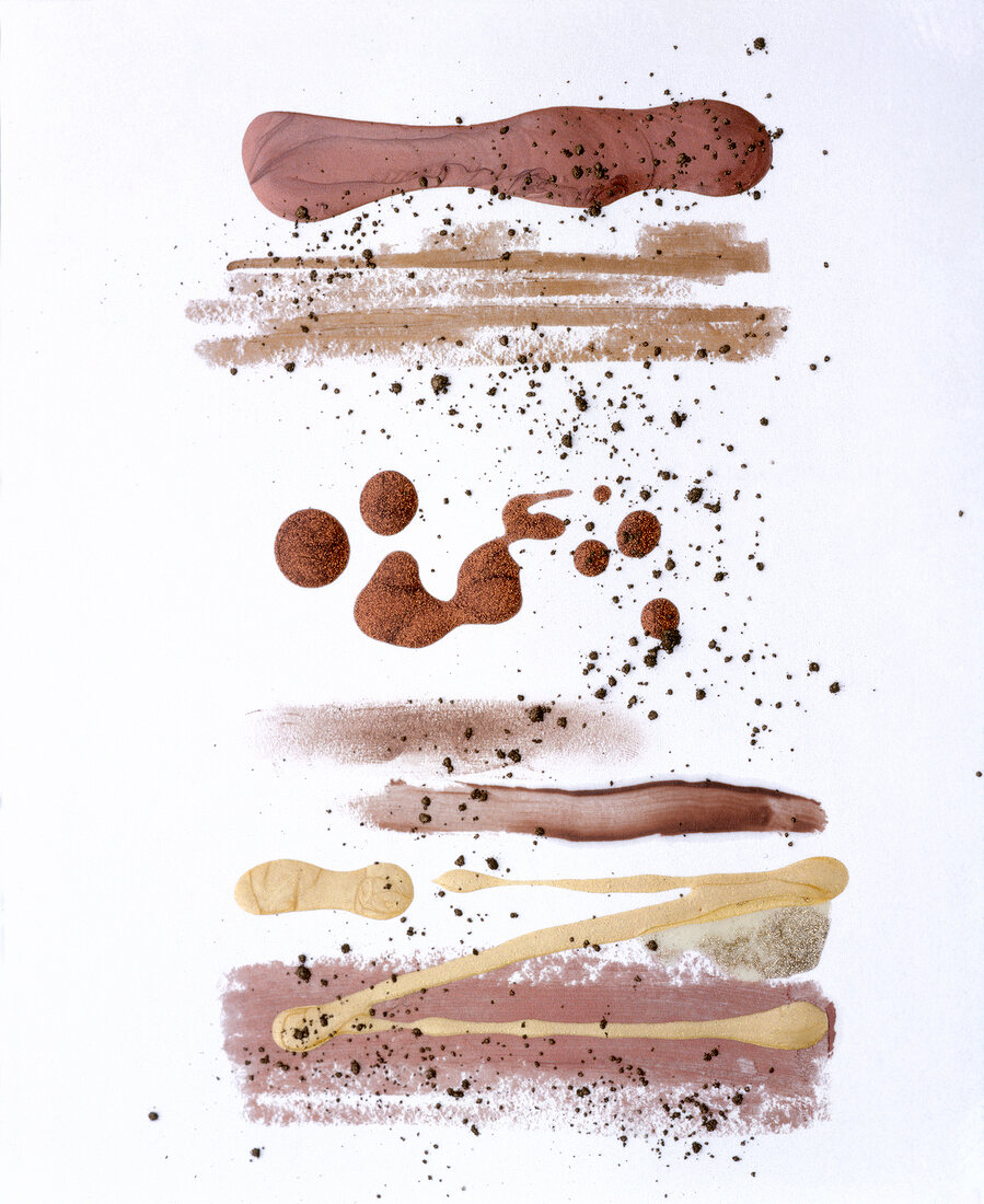 Close-up of golden and copper coloured make-up smeared on white background