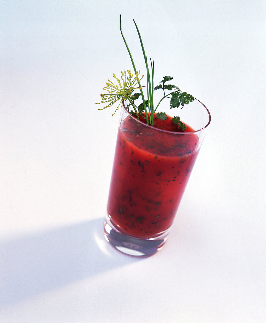 Ein Glas Tomatensaft mit Kräutern und einer Dillblüte dekoriert