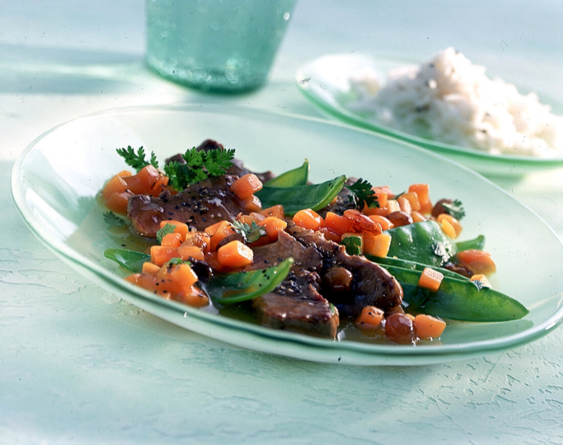 Lammfilet mit Zuckerschoten und Möhren auf hellgrünem Teller