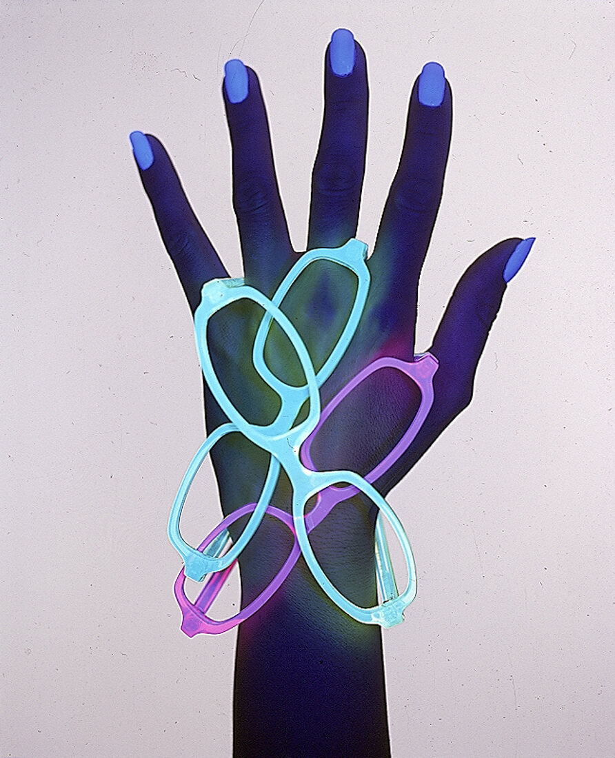 Frauenhand unter Schwarzlicht mit neonfarbenen Brillen