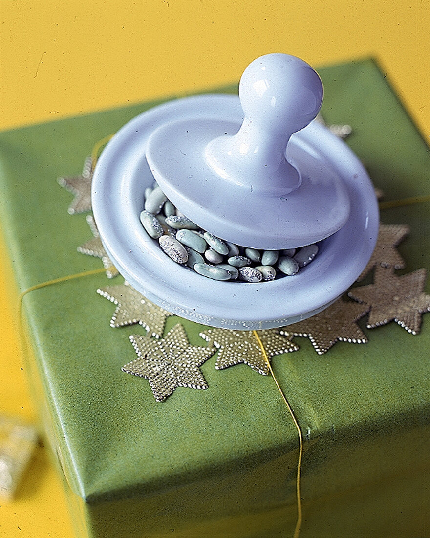 Weißer Porzellanmörser auf einem Weihnachtspäckchen