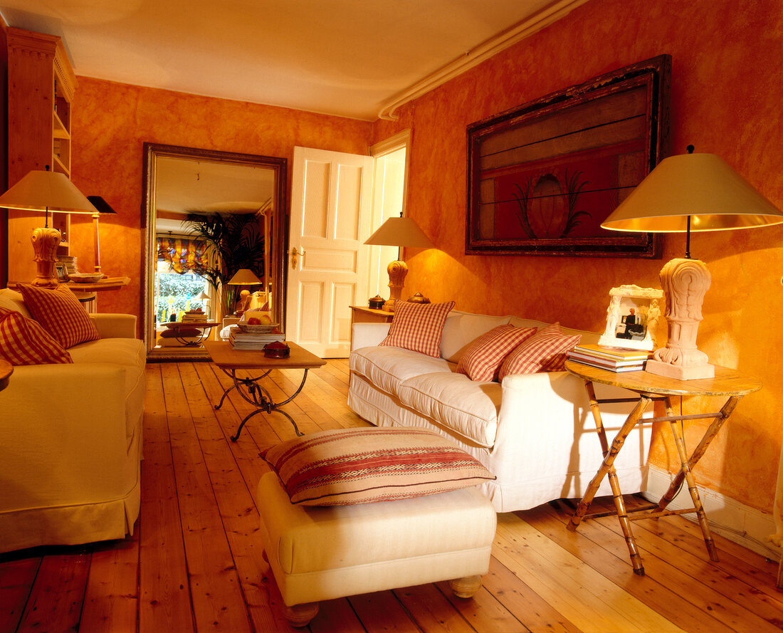 Interior of living room with orange walls, white chair and large mirror