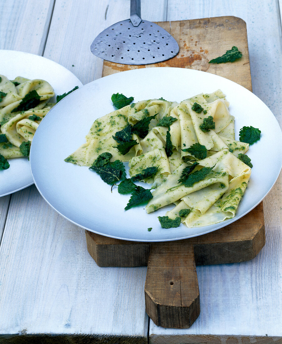 Open lasagne with wild herb salsa and nettle leaves on plate