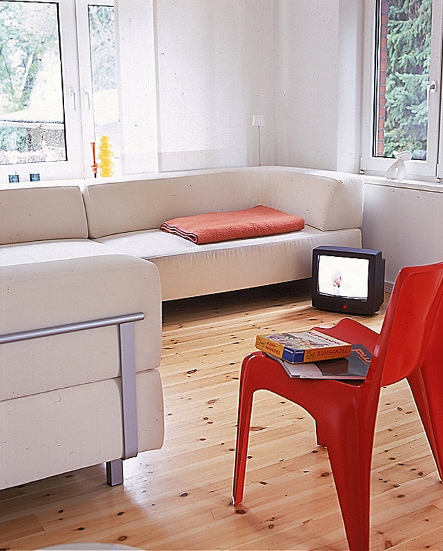 Wohnraum mit zwei weißen Sofas und rotem Kunststoffstuhl von H. Bätzner