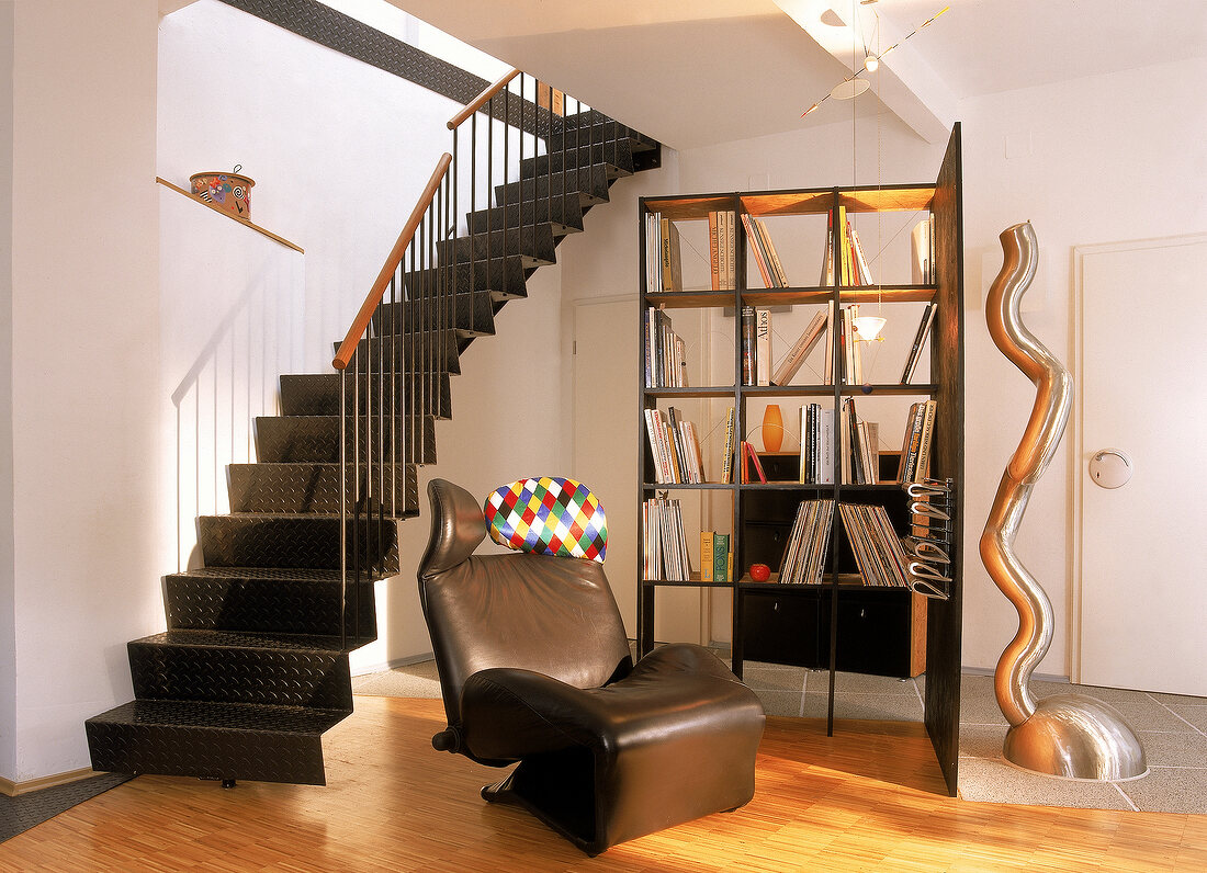 Freischwebende Treppe aus Metall, Sessel und Bücherregal