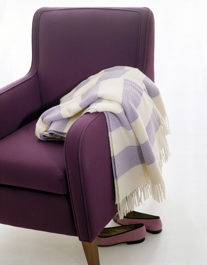Wolldecke hängt über d. lilafarbenen Sessel (lila Schuhe)