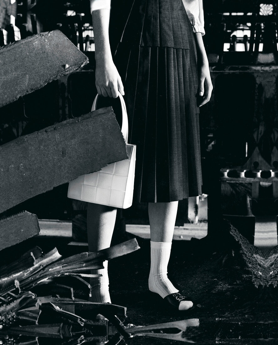 Close-up of woman wearing 50s style plaid skirt, white socks and holding handbag