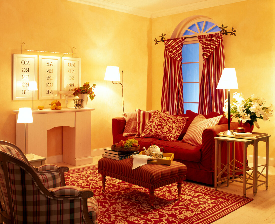 Area of living room with fire place, red sofa, and stripped curtain on window