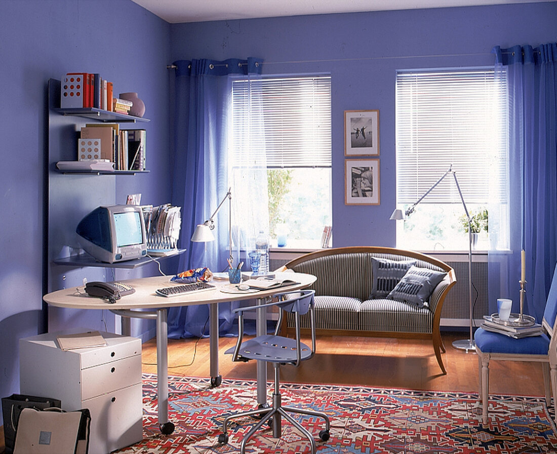 Arbeitszimmer in blau mit ovalem Schreibtisch, Sofa und Drehstuhl