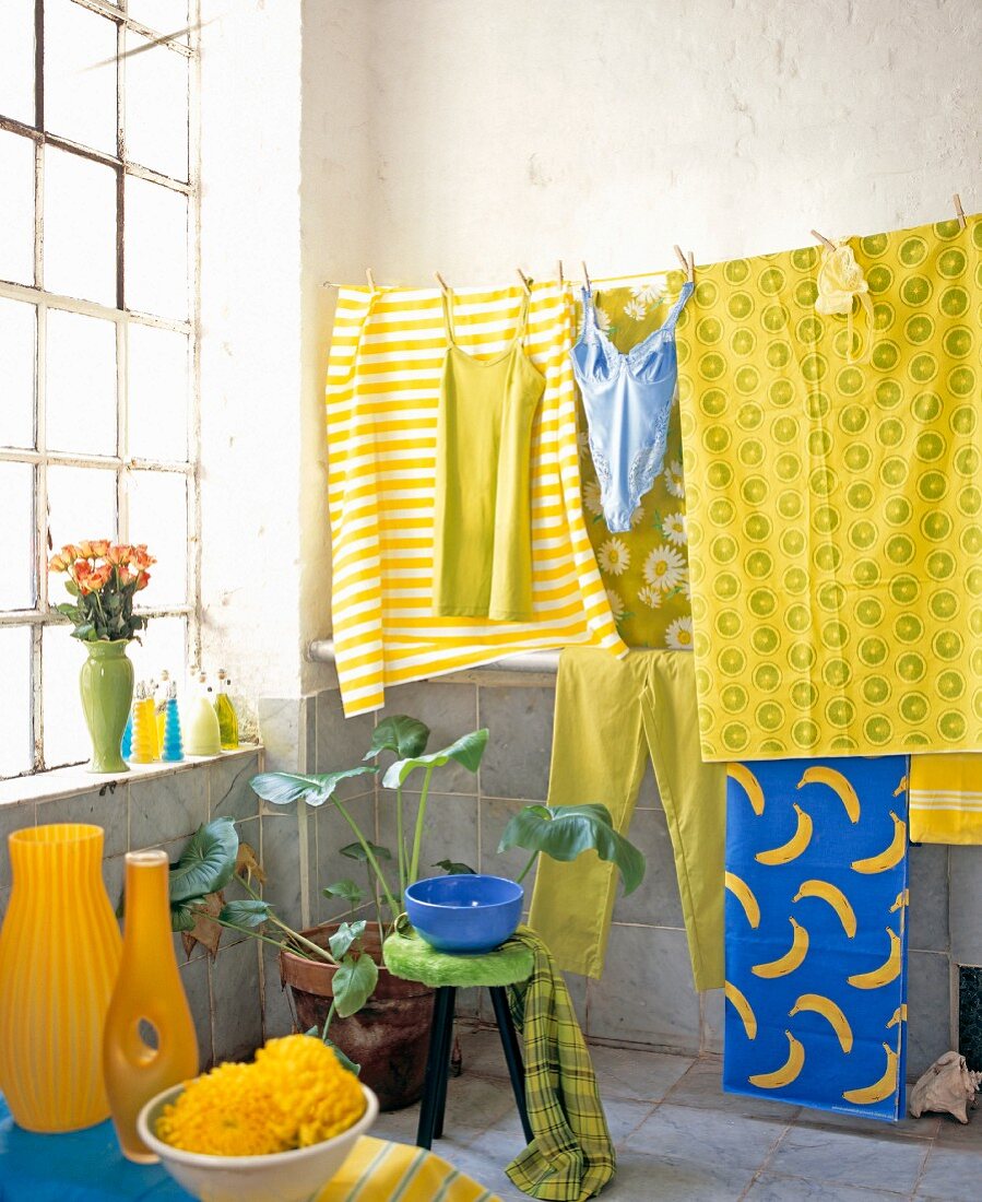 Farbige Wäsche hängt an Leine in loftartigem Badezimmer mit Sprossenfenster