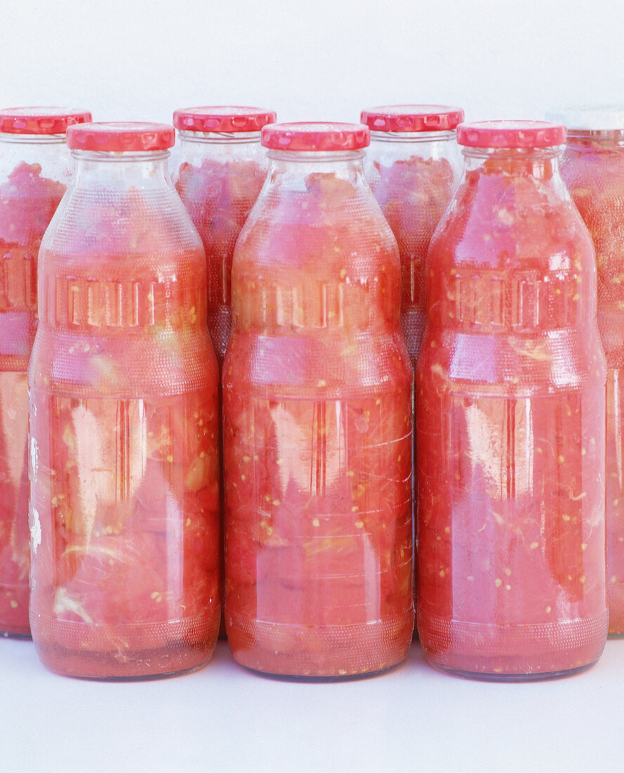 Geschälte und zerkleinerte Tomaten in Glasflaschen.