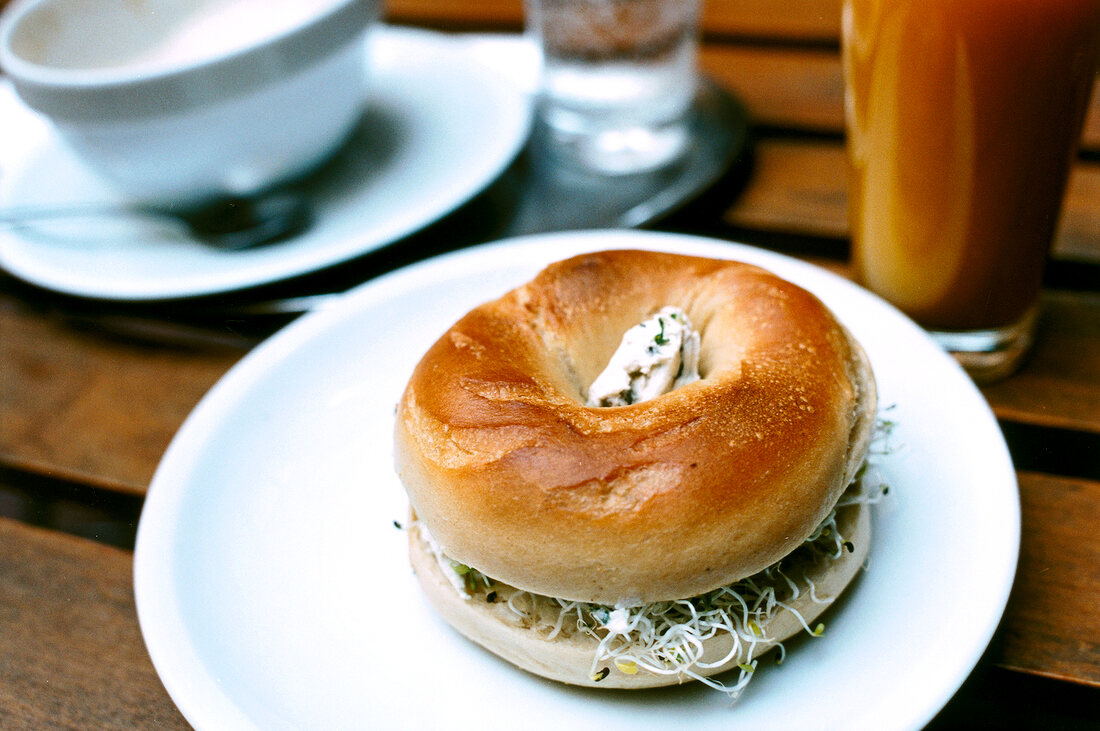 Bagel with cream cheese, sprouts and seedlings on plate