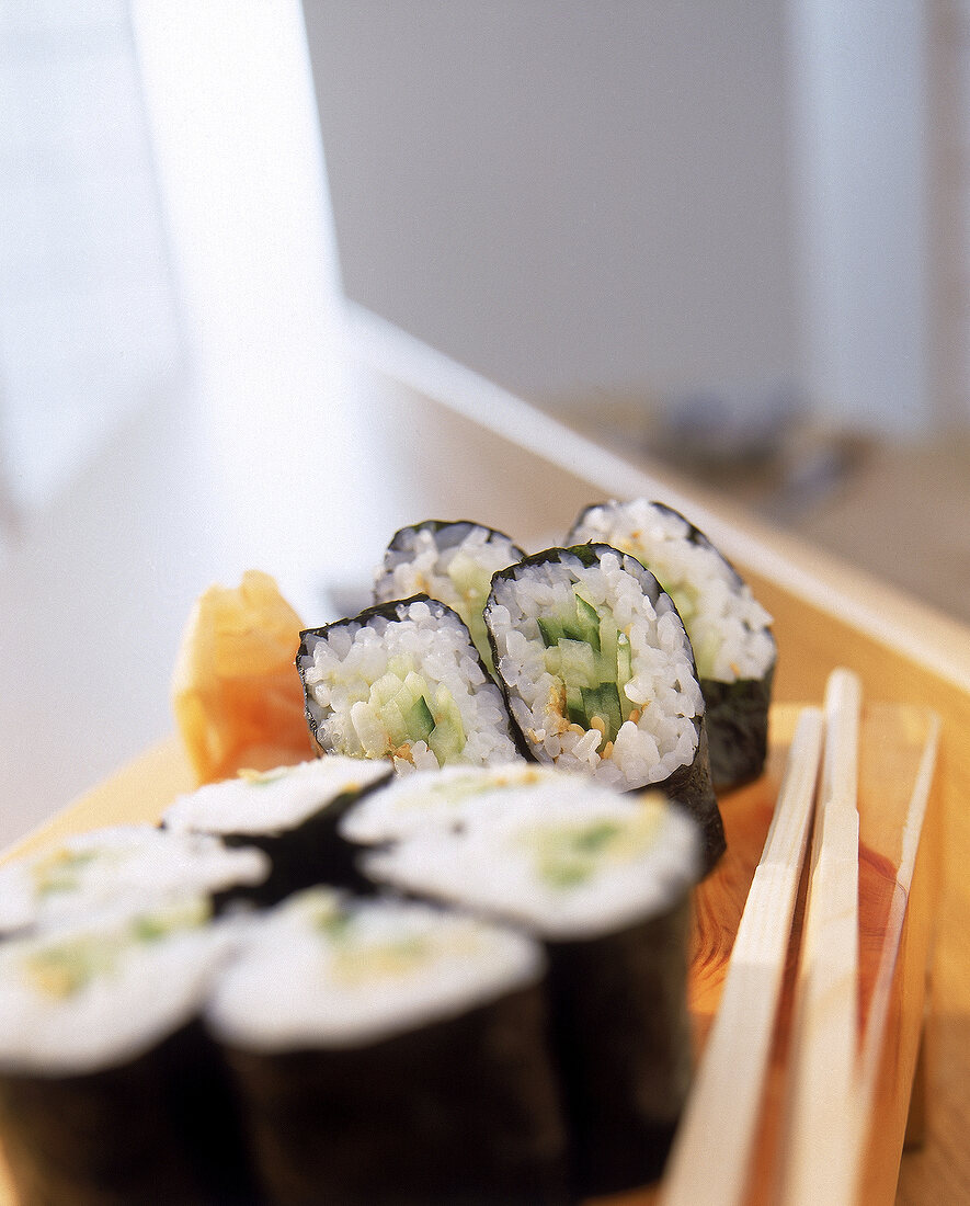 Sushi: 8 Stücke Kappamaki liegen auf einem Holzbrett, daneben Stäbchen