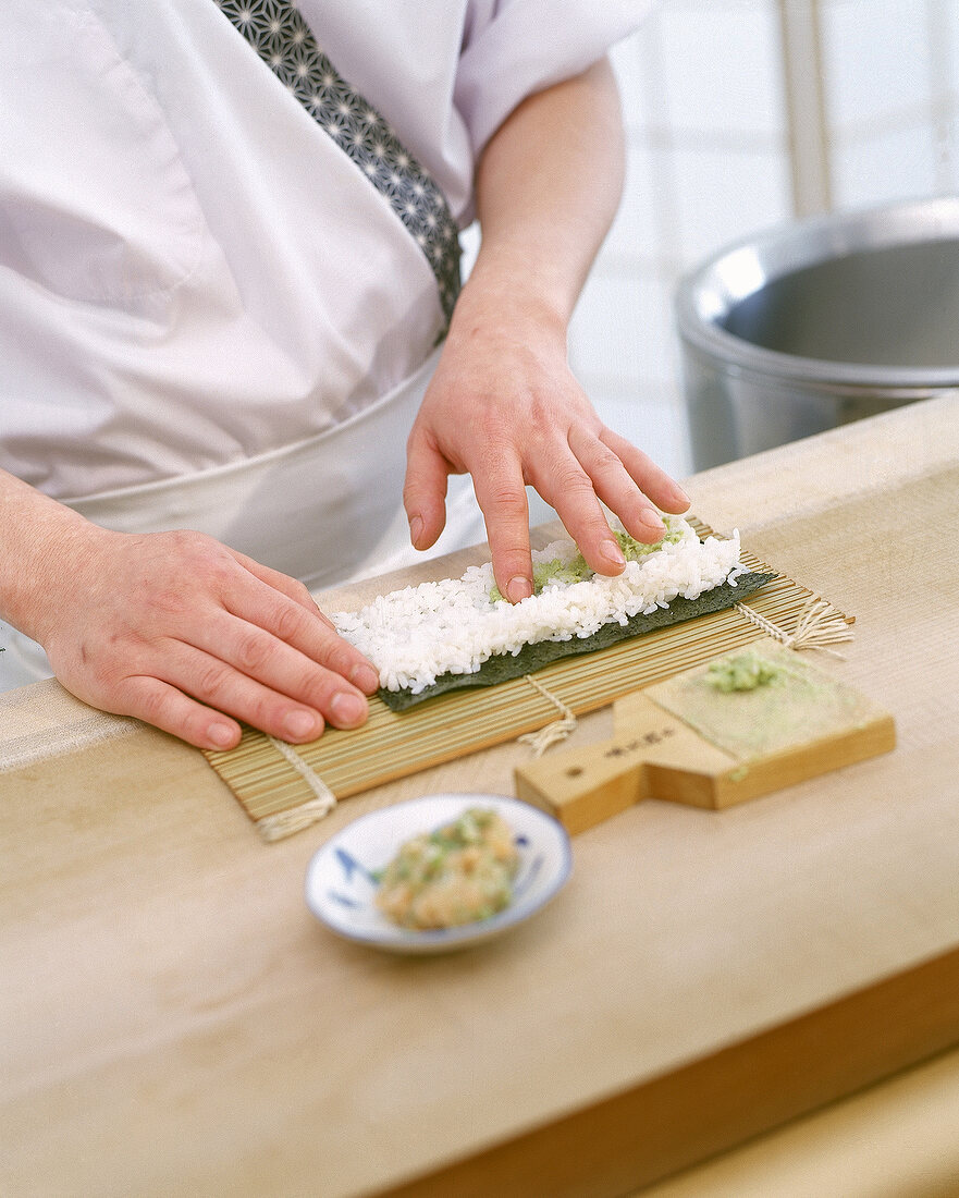 Step: Auf einer Sushimatte wird ein Algenblatt mit Reis belegt