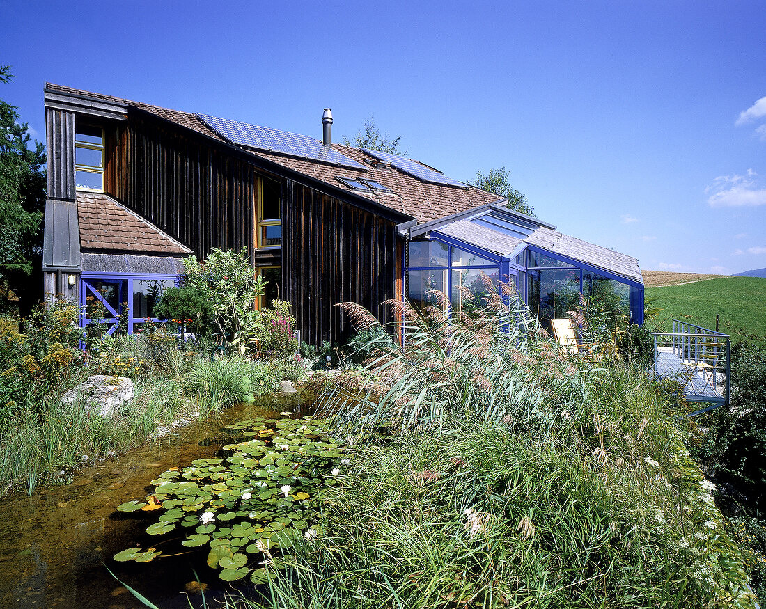 Einzelhaus mit vielen Glasflächen u. Photovoltaikzellen auf dem Dach.