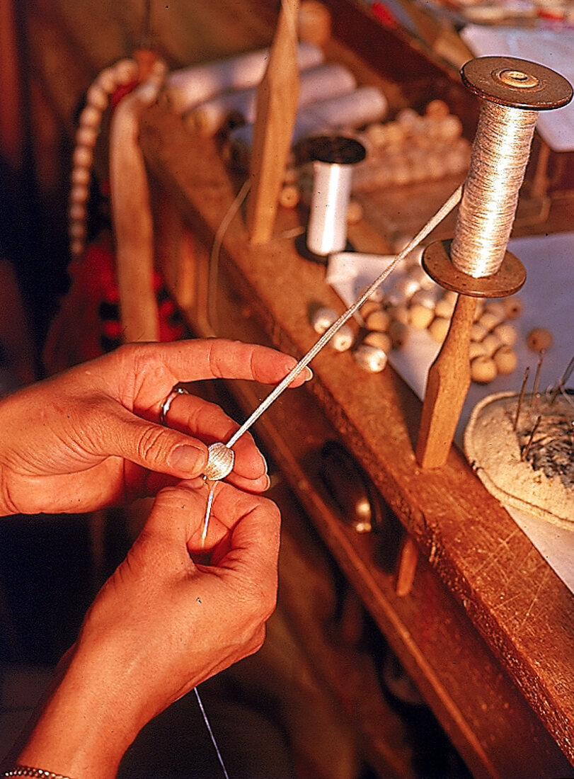 In handarbeit werden Perlen mit Garn umstochen