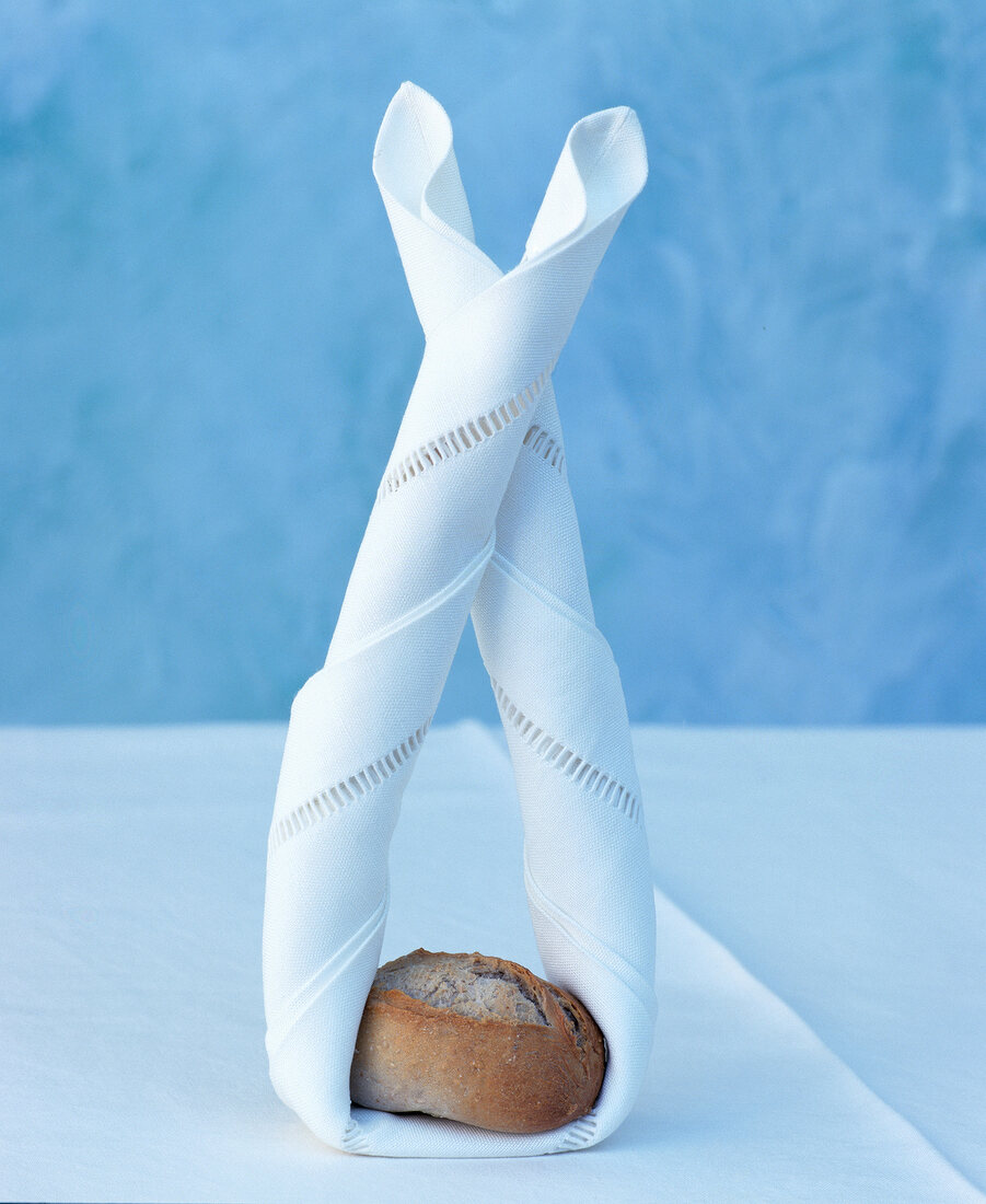 White linen napkin folded as Easter bunny with bread