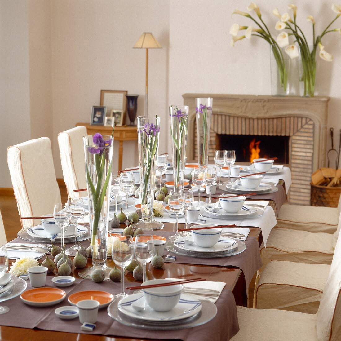 Asian table laid with crockery and tall vases with flowers