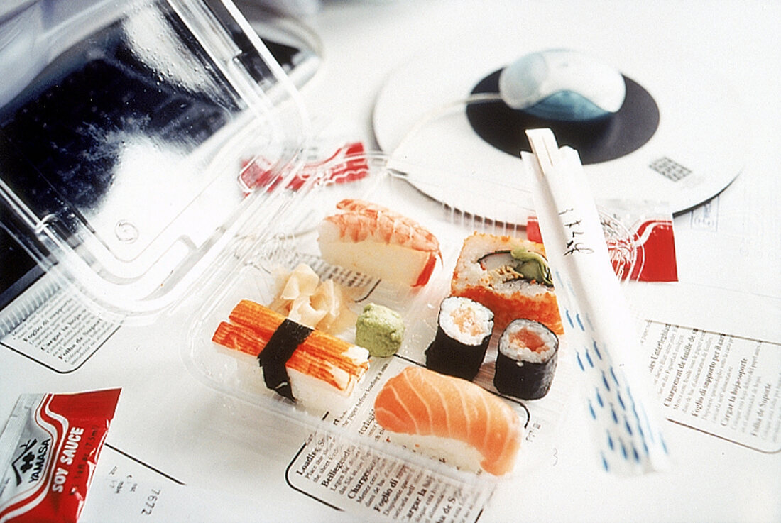 Sushi in einer Plastikschale auf dem Schreibtisch im Büro