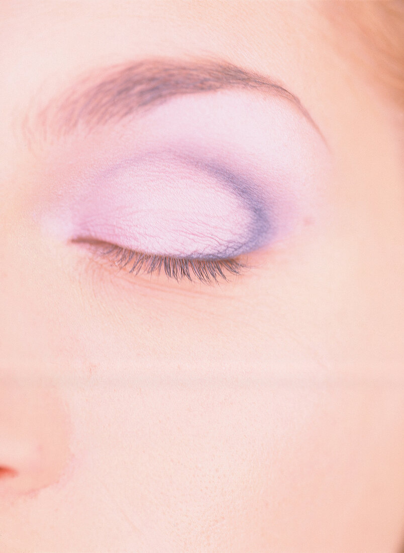 Extreme close-up of woman's eye wearing purple eye shadow