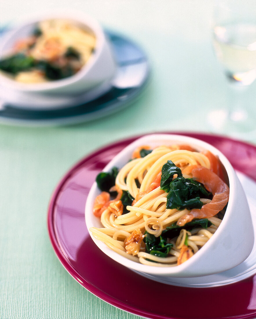 Bowl of spaghetti with salmon, spinach and lemon sauce on red plate