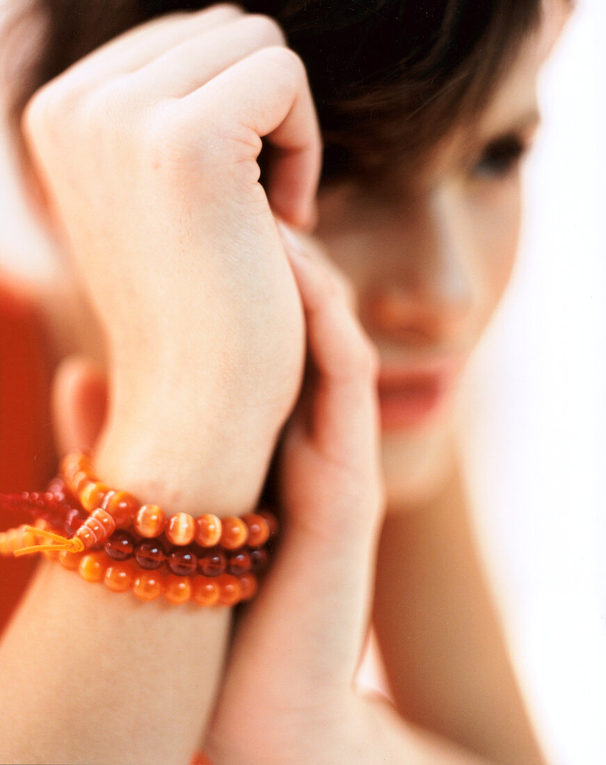 Buddhistische Gebetsarmbänder in Orangetönen am Handgelenk einer Frau