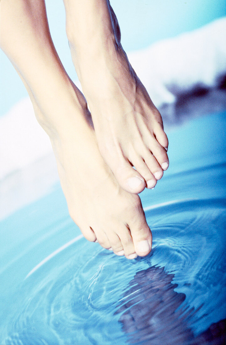 Close-up of feet being dipped in blue water