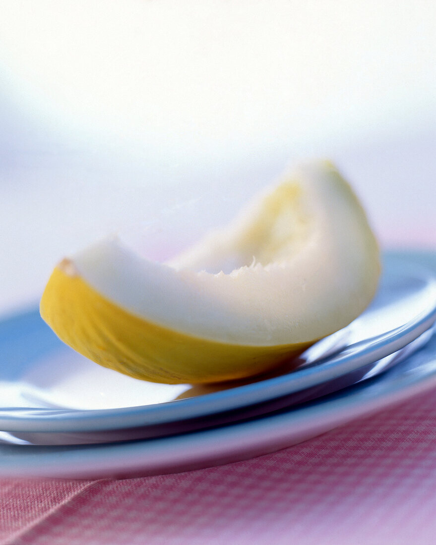 Aufgeschnittene Honigmelone auf zart blauem Teller, Unschärfe