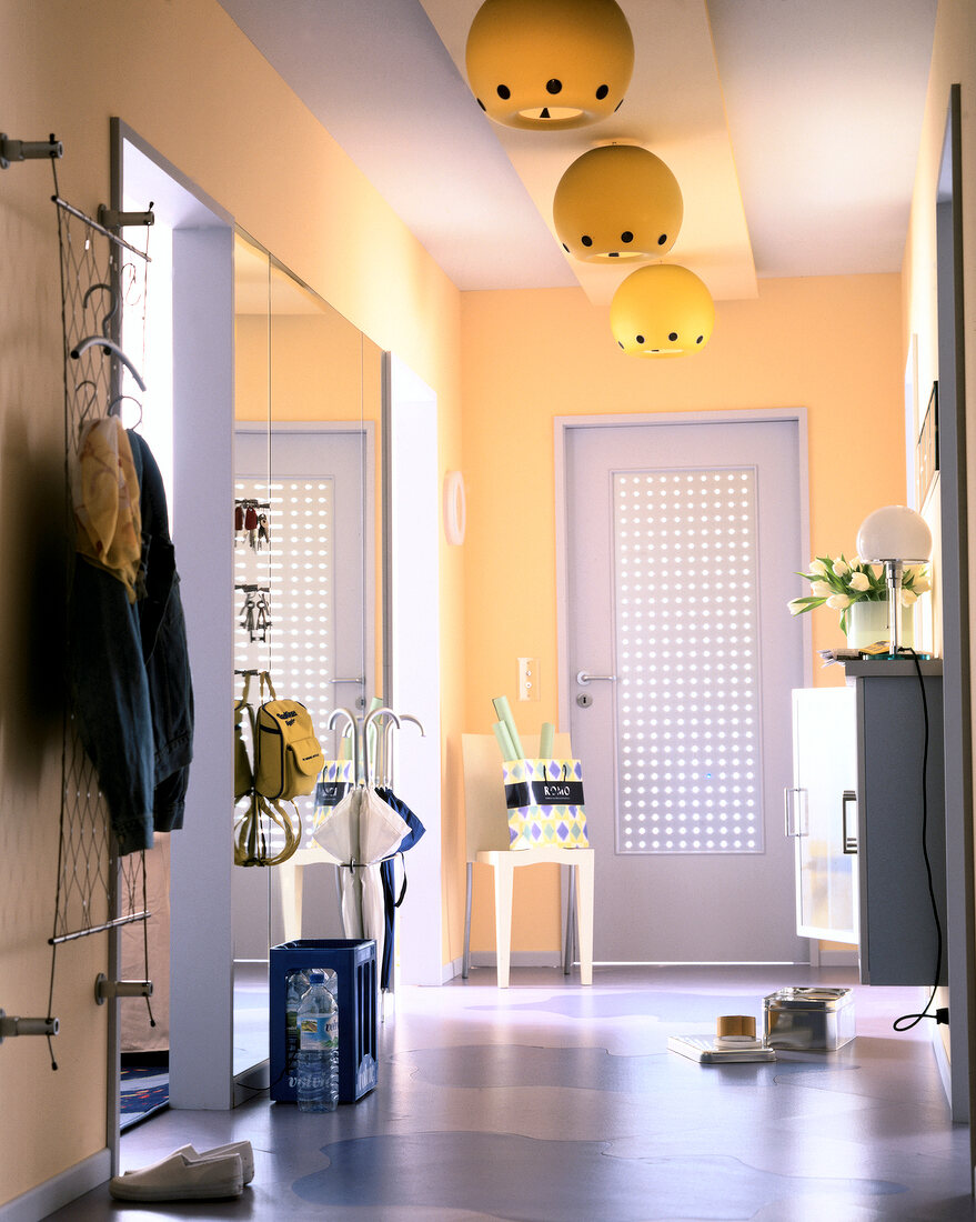 Yellow wall with large mirror, lamp, and perforated door in corridor