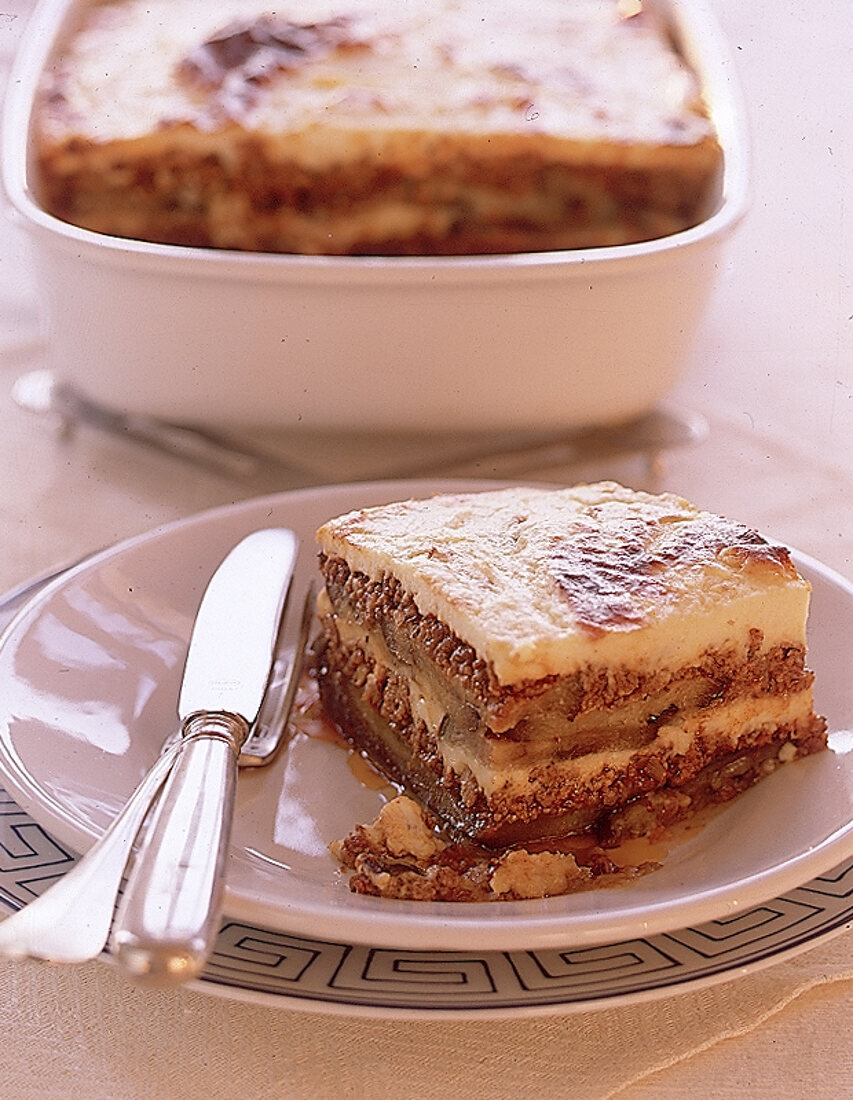 Stück Moussaka auf einem weißem Teller mit Besteck