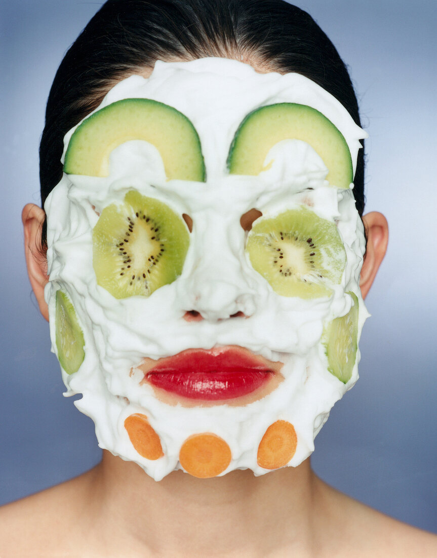 Close-up of woman wearing foam face mask with cucumber, avocado, kiwi and carrot