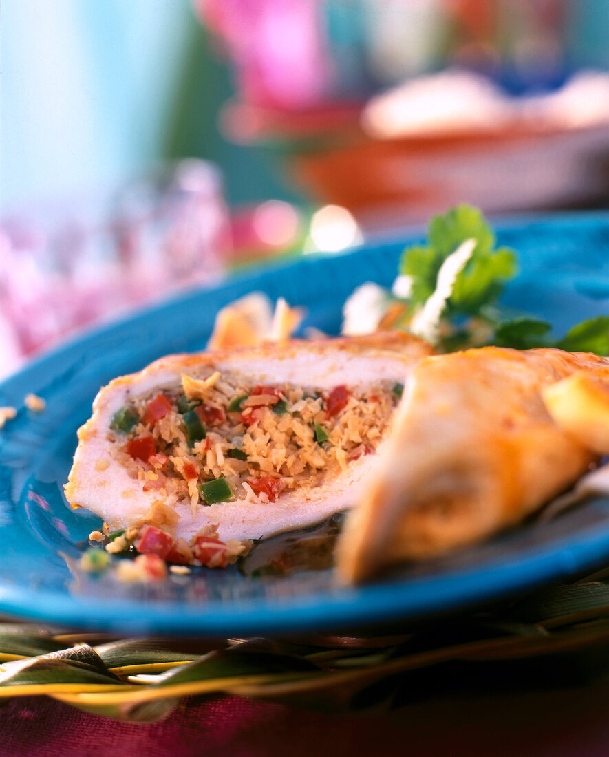 Close-up of chicken stuffed with coconut, peppers and coriander on blue plate