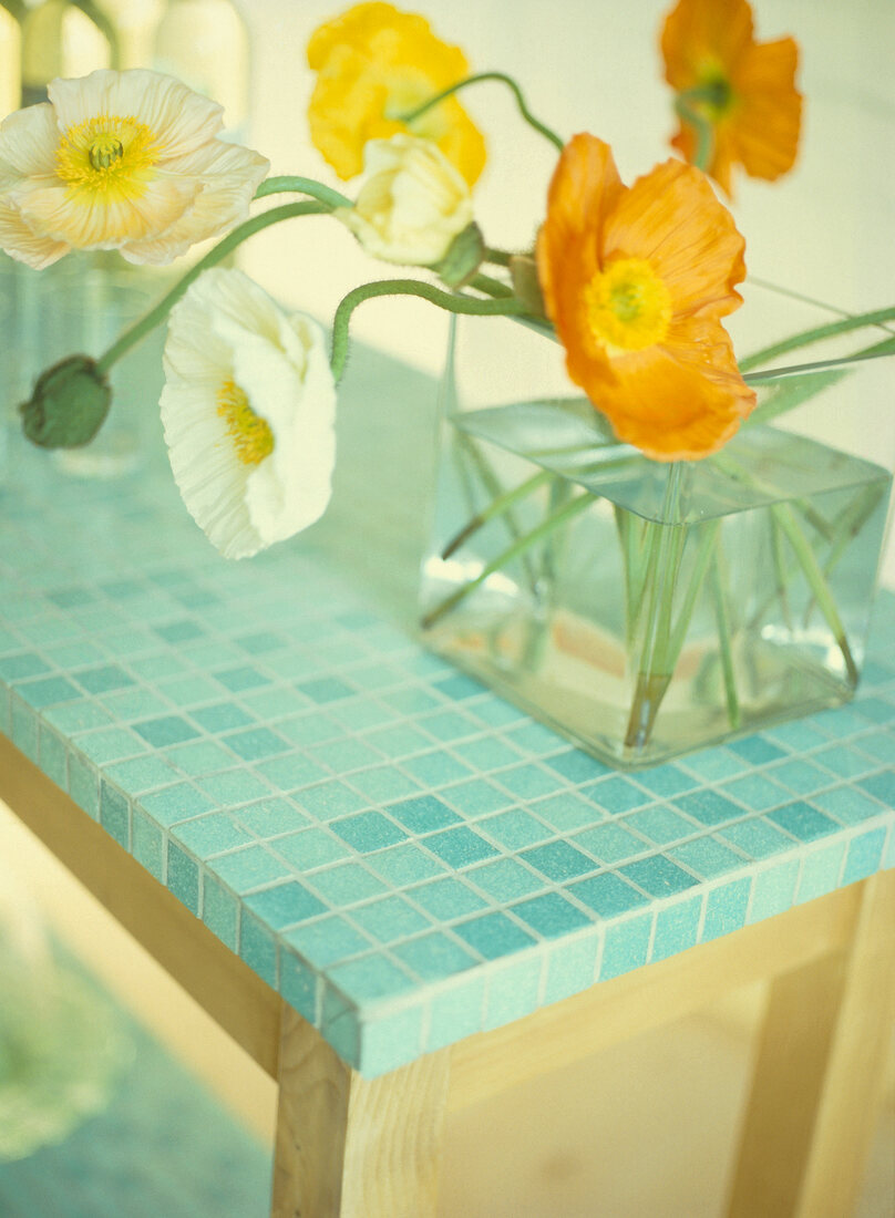 Vase of flowers on wooden table with mosaic tiles