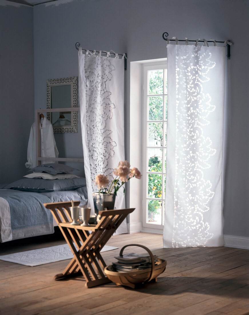 Mounted curtain on swivel arm, bed and wood table in bedroom