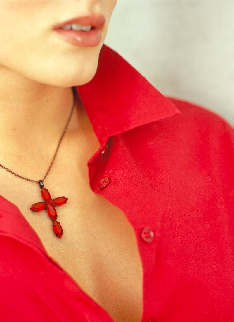 Close-up of woman wearing necklace with red cross pendant