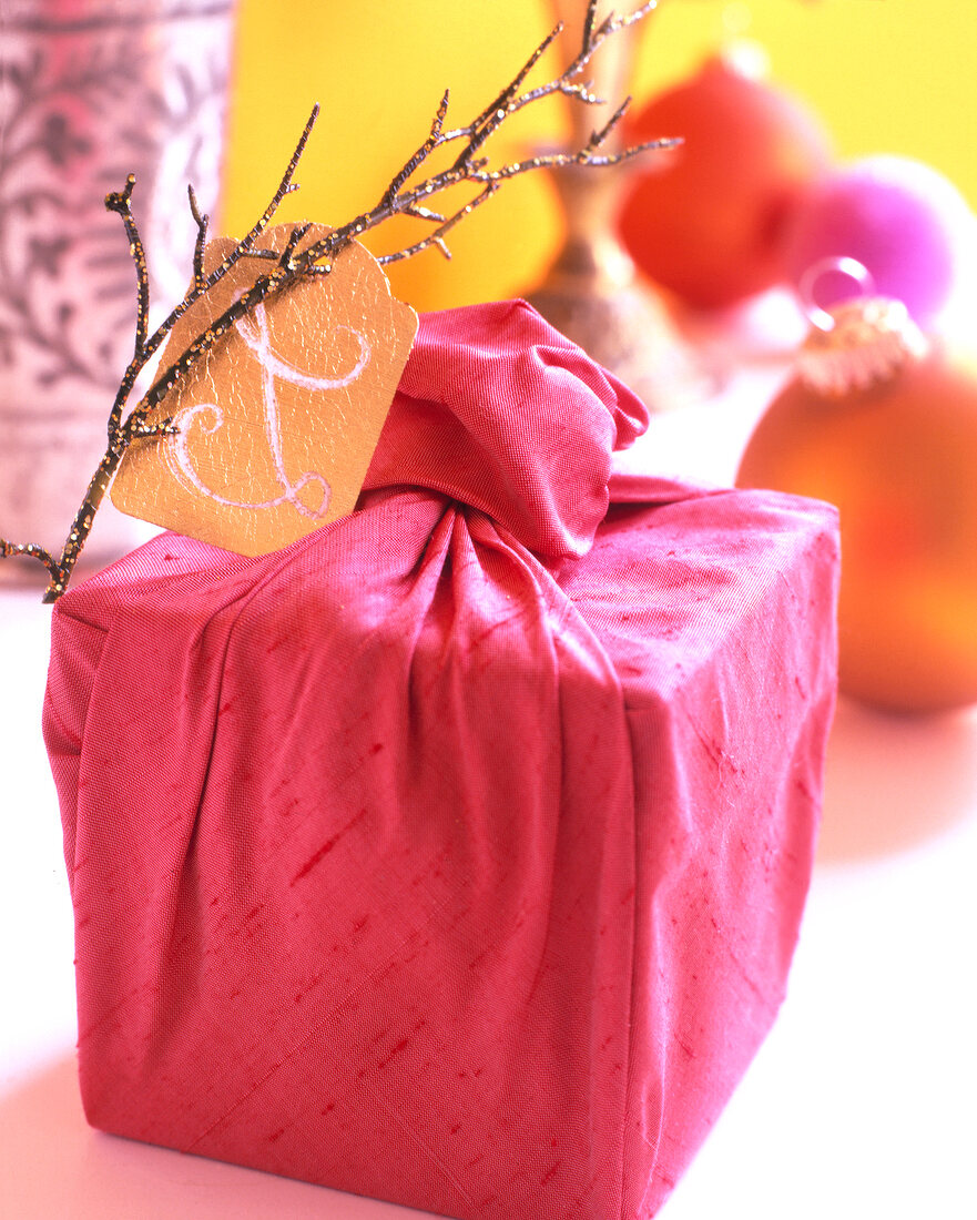 Geschenk, verpackt in pinkfarbene Seide mit Zweig und Goldkarte