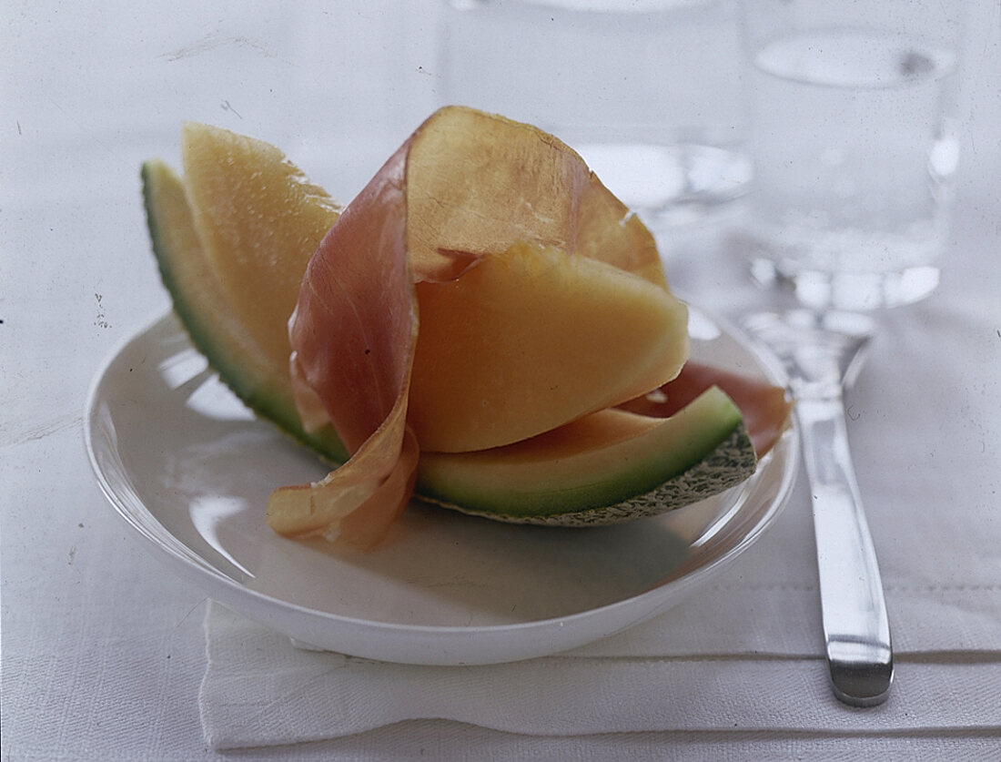 ein Stückchen frische Melone mit 1 Scheibe Parmaschinken