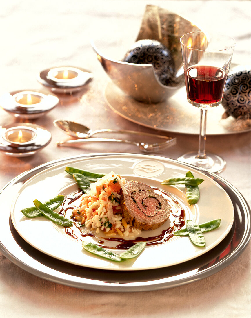 Beef tenderloin with tomato risotto, herbs and pine nuts on plate